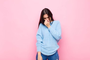 Genç ve güzel bir kadın iğreniyor. Pembe duvardaki pis ve nahoş kokuyu koklamamak için burnunu tutuyor.