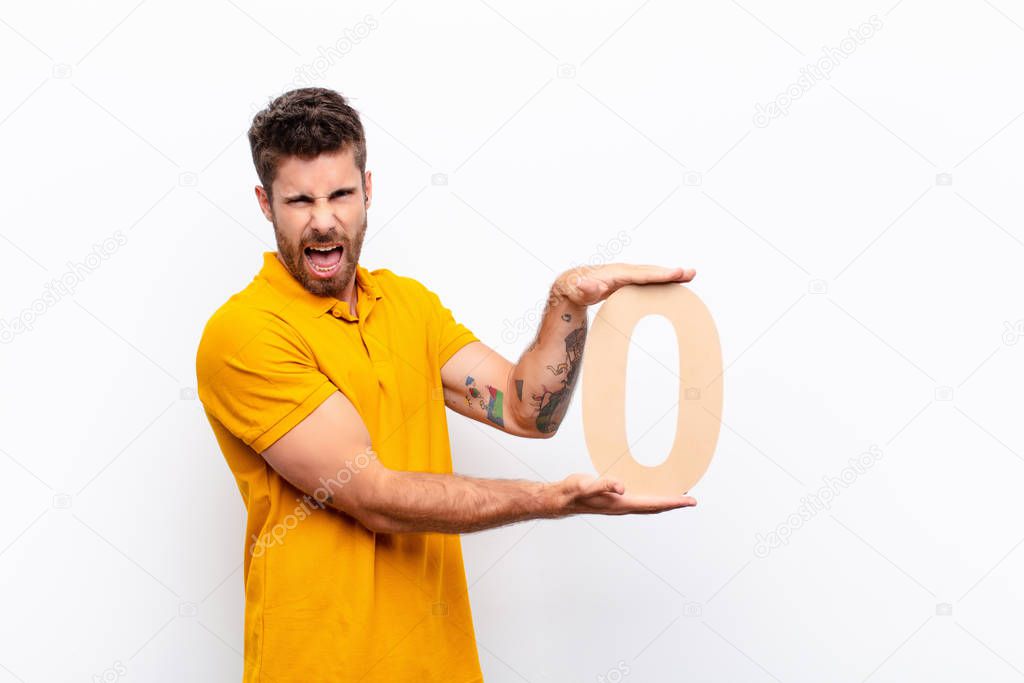 young handsome man angry, anger, disagreement, holding a number 0.