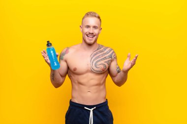 Genç sarışın güçlü adam mutlu, heyecanlı, şaşırmış ya da şok olmuş hissediyor, gülümsüyor ve enerji içeceğiyle inanılmaz bir şeye şaşırıyor.