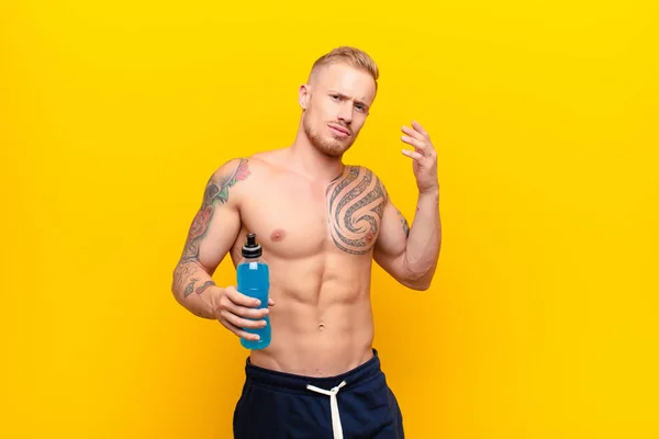 young blonde strong man feeling stressed, anxious, tired and frustrated, pulling shirt neck, looking frustrated with problem with an energy drink