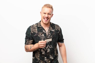 Genç sarışın adam tiksinti ve tedirginlik duyuyor, dilini dışarı çıkarıyor, kötü bir şeyden hoşlanmıyor ve kredi kartıyla iğreniyor.