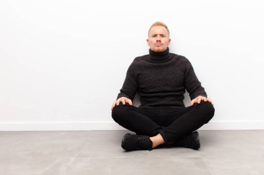 Genç sarışın adam dudaklarını birbirine bastırıyor, tatlı, eğlenceli, mutlu, sevimli bir yüz ifadesiyle, çimento zeminde oturan bir öpücük yolluyor.