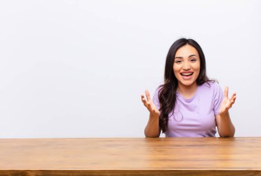 Genç Latin güzel kadın kendini mutlu, şaşkın, şanslı ve şaşırmış hissediyor. Sanki her şeyi ciddiye alıyormuş gibi. Düz duvara karşı inanılmaz.