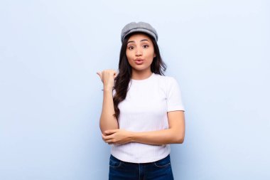 Genç Latin, güzel bir kadın inançsızlıktan şaşkın şaşkın bakıyor, yan taraftaki objeyi işaret ediyor ve 