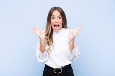 Genç, güzel İspanyol bir kadın mutlu ve heyecanlı görünüyor. Beklenmedik bir sürprizle şoke olmuş durumda. İki eli de mavi duvara karşı açık.