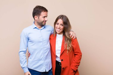 Genç ve güzel bir çift bej düz duvara karşı