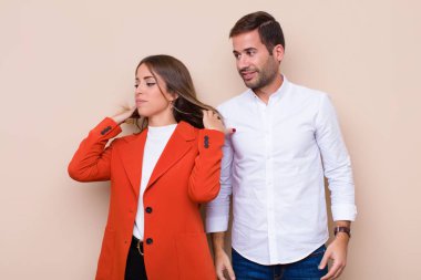 Genç ve güzel bir çift bej düz duvara karşı