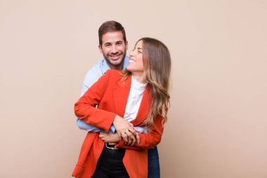 Genç ve güzel bir çift bej düz duvara karşı