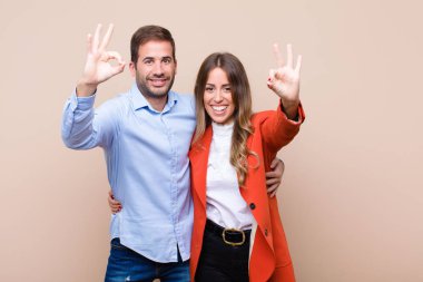 Genç ve güzel bir çift bej düz duvara karşı