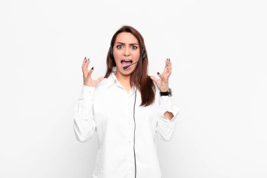 Genç ve güzel bir kadın ellerini havaya kaldırıp bağırıyor. Öfkeli, sinirli, stresli ve mikrofon ve kulaklıklardan rahatsız oluyor.