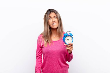 Genç ve güzel bir kadın şaşkın ve kafası karışmış görünüyor. Sinirli bir hareketle dudağını ısırıyor. Çalar saati tutan sorunun cevabını bilmiyor..