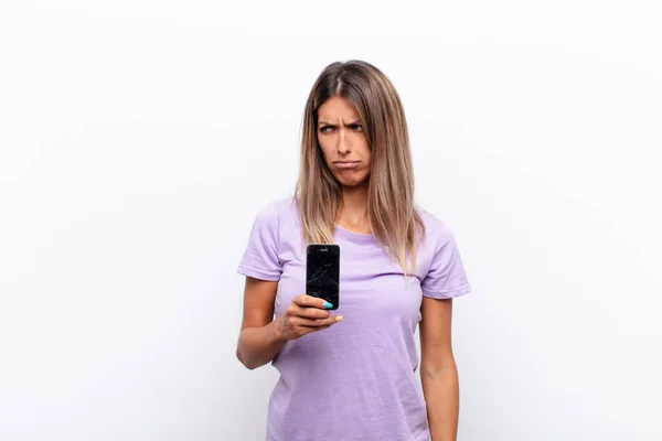 若いきれいな女性は悲しい 動揺や怒りを感じ 否定的な態度で側面を見て スマートフォンを保持する意見の相違に眉をひそめて — ストック写真