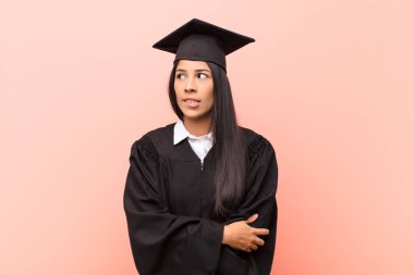 Genç Latin kız öğrenci şüpheye düşüyor ya da düşünüyor, dudağını ısırıyor ve kendini güvensiz ve gergin hissediyor, kenarda yer arıyor.