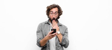 Genç çılgın adam akıllı telefonunu beyaz duvara karşı kullanıyor.