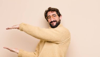 Genç havalı adam gülümsüyor, mutlu, pozitif ve tatmin olmuş hissediyor, fotokopi odasında düz duvara karşı nesne ya da konsept tutuyor ya da gösteriyor