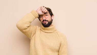 Stresli, yorgun ve hayal kırıklığına uğramış, alnından ter damlayan, umutsuz ve bitkin hisseden genç bir adam.