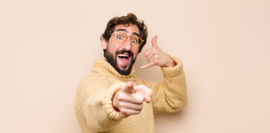 Genç havalı adam neşeyle gülümsüyor ve kamerayı işaret ediyor. Daha sonra seni arıyor, telefonda düz duvara karşı konuşuyor.