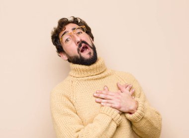 Genç havalı adam üzgün, incinmiş ve kalbi kırık görünüyor, iki elini de kalbe yakın tutuyor, ağlıyor ve yassı duvara karşı depresyona giriyor.