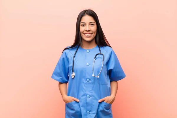 若いラテン語の看護師は明るく気軽に笑顔で ピンクの壁に対してポジティブで幸せ 自信とリラックスした表情で — ストック写真