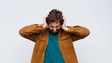 Genç ve yakışıklı bir adam stresli ve hayal kırıklığına uğramış hissediyor. Yumruk yumruğa, yorgun, mutsuz ve migreni düz duvara dayanmış.