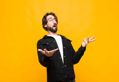 Genç çılgın yakışıklı adam opera yapıyor veya konserde şarkı söylüyor, romantik, sanatsal ve turuncu duvara karşı tutkulu hissediyor