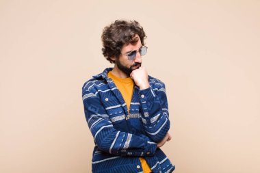 Genç, çılgın, havalı bir adam ciddi, düşünceli ve kaygılı. Elleri çenesine yaslanmış bir şekilde duvara bakıyor.