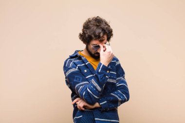 Genç çılgın havalı adam stresli, mutsuz ve hayal kırıklığına uğramış, alnına dokunuyor ve düz duvara karşı şiddetli baş ağrısı çekiyor.