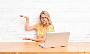 Genç sarışın bir kadın, iki eli de yan tarafında olan bir objeyi tutuyor. Kopya boşluğunda, bir objeyi sunuyor, sunuyor ya da tanıtıyor.