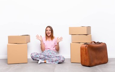 Kızıl saçlı güzel bir kadın mutlu ve heyecanlı görünüyor. Beklenmedik bir sürprizle şoke oldu. İki eli de yeni bir evde yan yana açık.