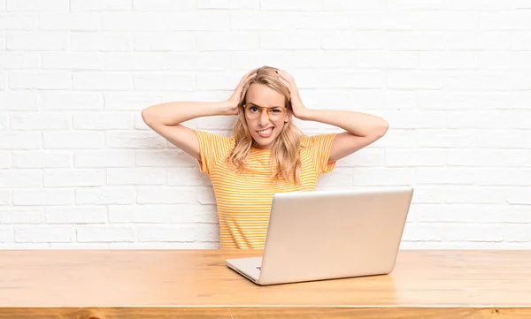 若いブロンドの女性はフラストレーションを感じていらいらし 病気になり 失敗に疲れて ノートパソコンを使用して退屈な仕事でうんざりしています — ストック写真