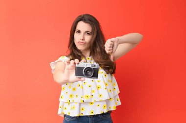 Kırmızı duvarda eski model fotoğraf makinesi olan genç ve güzel bir kadın.