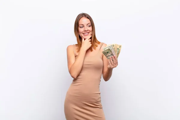 幸せそうな表情で微笑む赤い頭の女性顎を手に銀行券を手に — ストック写真