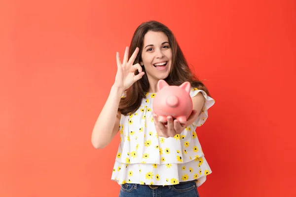 Jovem Mulher Bonita Contra Parede Vermelha Segurando Piggybank — Fotografia de Stock