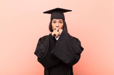 Genç Latin kız öğrenci ciddi görünüyor ve iki parmağının önde olması hoşnutsuzluk yaratıyor. Sessizlik istiyor.