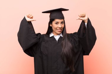 Genç Latin kız öğrenci gururlu, kibirli ve kendinden emin, tatmin olmuş ve başarılı görünüyor, kendini işaret ediyor.