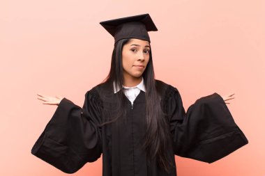 Genç Latin kız öğrenci şaşkın ve şaşkın hissediyor, doğru cevap veya karardan emin değil, bir seçim yapmaya çalışıyor.