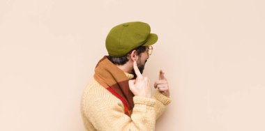 Genç, havalı sakallı, kötü tavırlı, gururlu ve agresif görünümlü, yukarıyı gösteren ya da elleriyle alay eden bir adam.