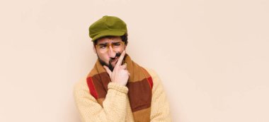 Genç havalı sakallı adam, kafası karışık ve şüpheli hissediyor, merak ediyor ya da karar vermeye çalışıyor.