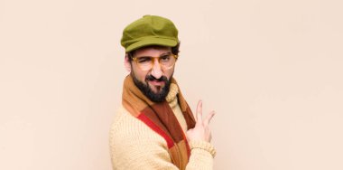 Genç, havalı sakallı adam mutlu, pozitif ve başarılı hissediyor. Göğsünde el ile zafer ya da barış işareti yapıyor.