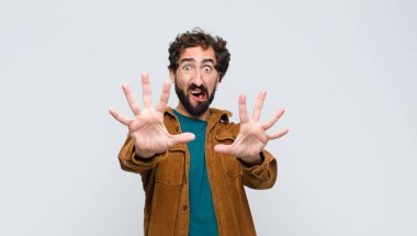 Dehşete kapılmış genç yakışıklı bir adam korku ve panik içinde geri çekiliyor ve düz duvara karşı bir kabusa tepki veriyor.