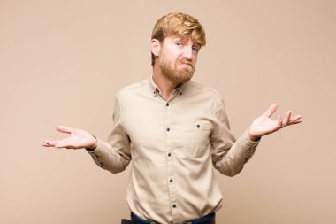 Genç sarışın adam şaşkın ve şaşkın hissediyor, doğru cevap veya karardan emin değil, düz duvara karşı bir seçim yapmaya çalışıyor.