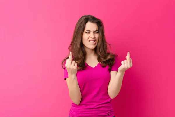 ピンクの壁に反抗的な態度で中指をひっくり返して挑発的で攻撃的で卑猥な感じの若い可愛い女性 — ストック写真