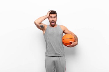 Genç ve yakışıklı bir adam el ele tutuşuyor, ağzı açık, son derece şanslı, şaşırmış, heyecanlı ve mutlu bir şekilde elinde basketbol topu tutuyor..