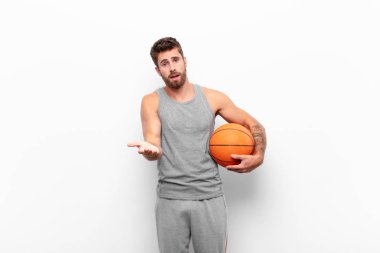 Genç yakışıklı adam mutlu ve aşık, bir eli kalbinin yanında gülümsüyor ve diğeri de elinde basketbol topuyla önde uzanıyor..