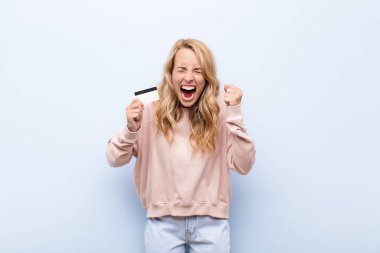 Genç sarışın kadın agresif bir şekilde bağırıyor, kızgın, hayal kırıklığına uğramış, kızgın ya da kızgın görünüyor, bağırıyor, elinde kredi kartı yok.