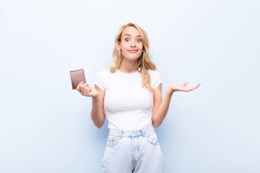 Genç sarışın kadın şaşkın ve şaşkın, şüpheci, farklı seçenekleri tartıyor ya da seçiyor.