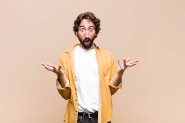 Genç, havalı, ağzı açık ve şaşırmış, şaşırmış ve şaşırmış genç bir adam düz duvara karşı inanılmaz bir sürprizle