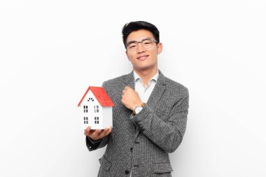 Genç japon adam mutlu, pozitif ve başarılı hissediyor, bir meydan okumayla karşılaştığında motive oluyor ya da ev modeliyle iyi sonuçları kutluyor.