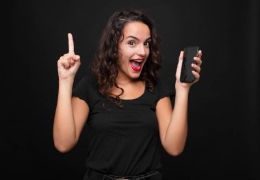 Genç ve güzel bir kadın bir fikri fark ettikten sonra mutlu ve heyecanlı bir dahi gibi hissediyor, neşeli bir şekilde parmağını kaldırıyor, eureka! Elinde akıllı telefon var.