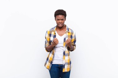 Genç, güzel, siyah bir kadın sinirli, sinirli, kızgın bakışlar ve sıkı yumruklar ile agresif bir şekilde bağırıyor.